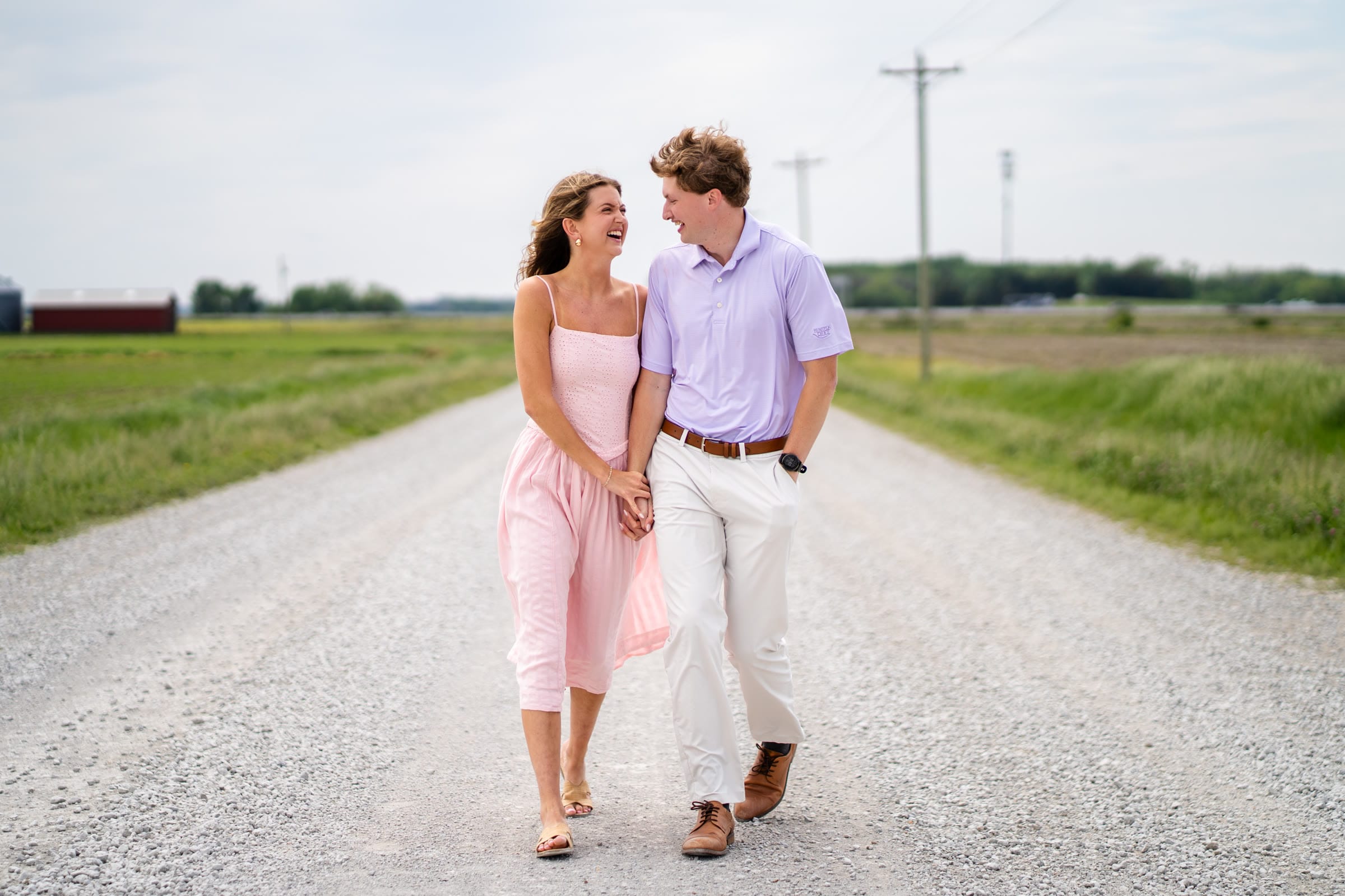 Engaged couple laughing while walking down a gravel road