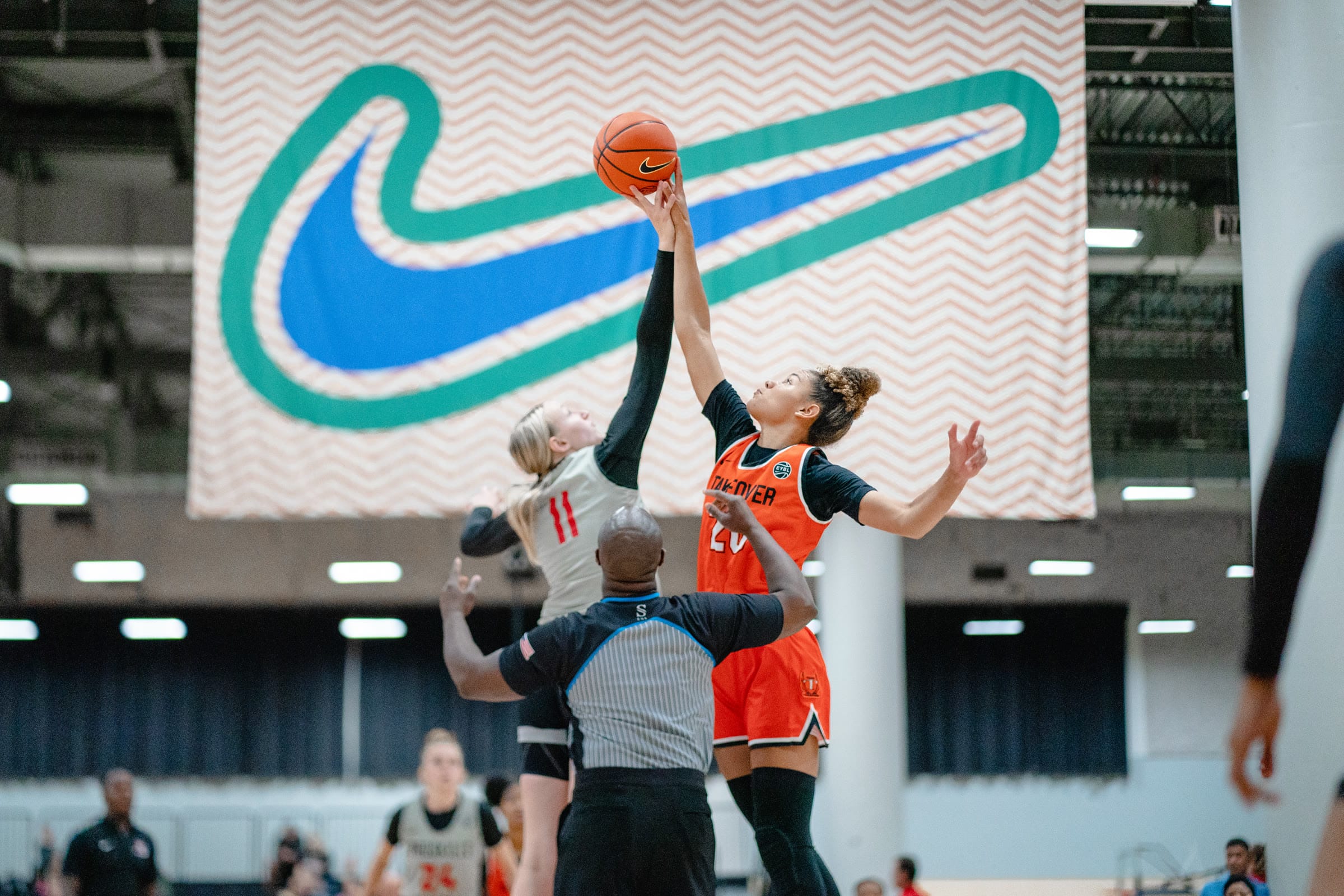 Two basketball players battling for a jump ball under the Nike EYBL banner