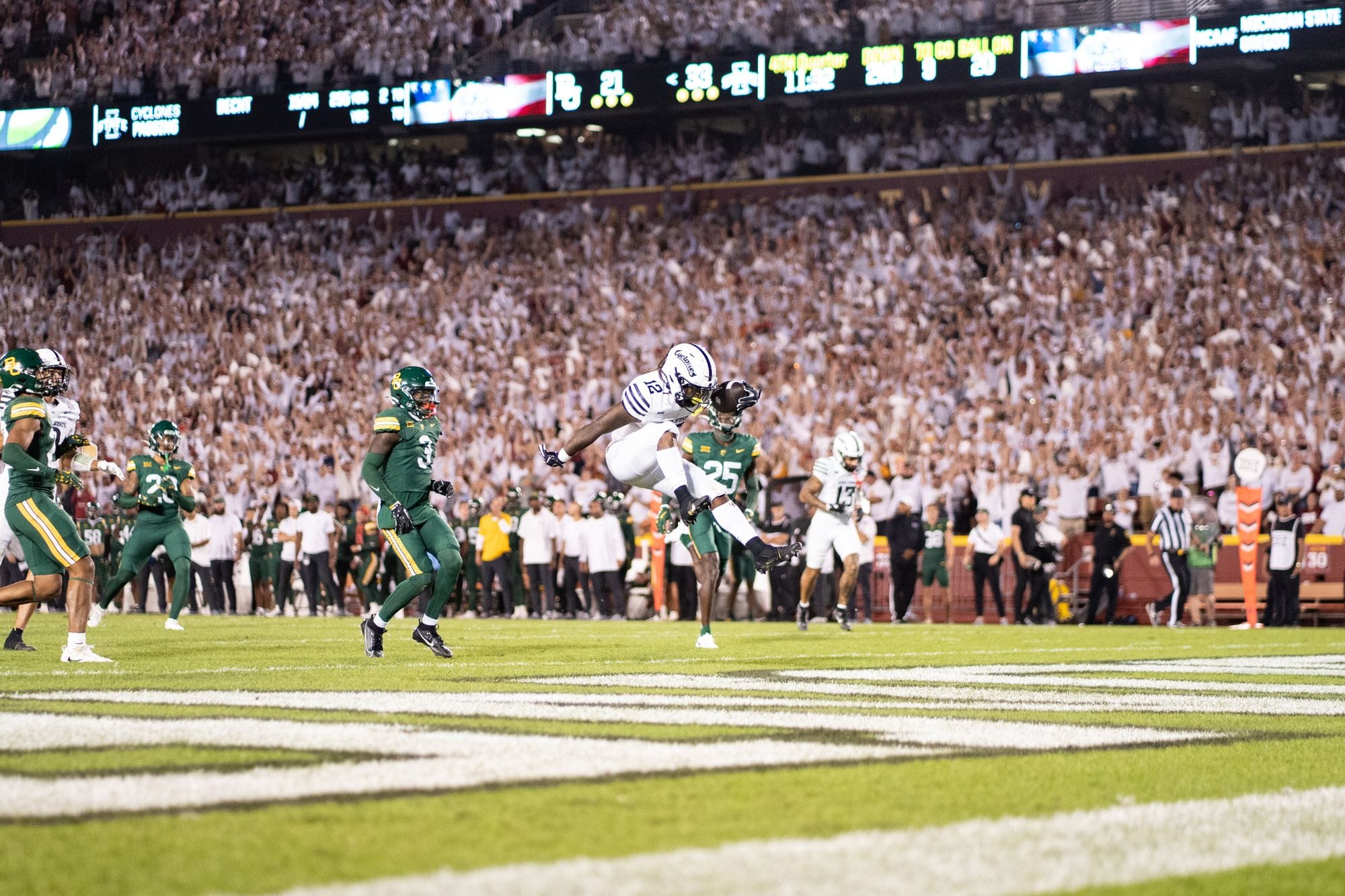 Football player diving into the end zone during a night game