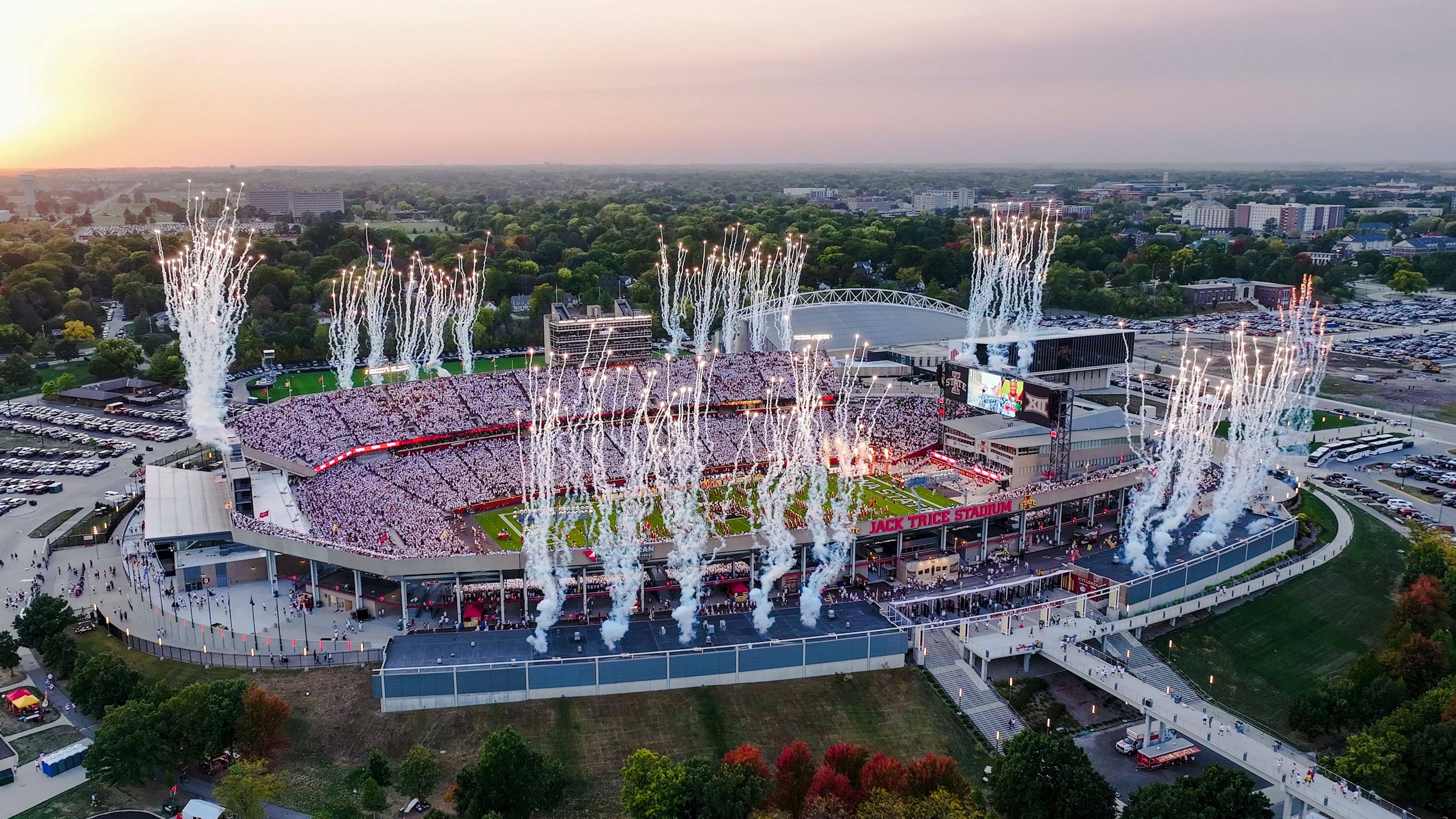 Aerial view of a fireworks show over Jack Trice Stadium at dusk